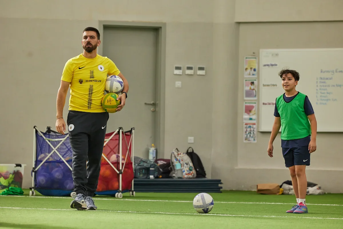 A coach leading a training session with a young player at the Academy