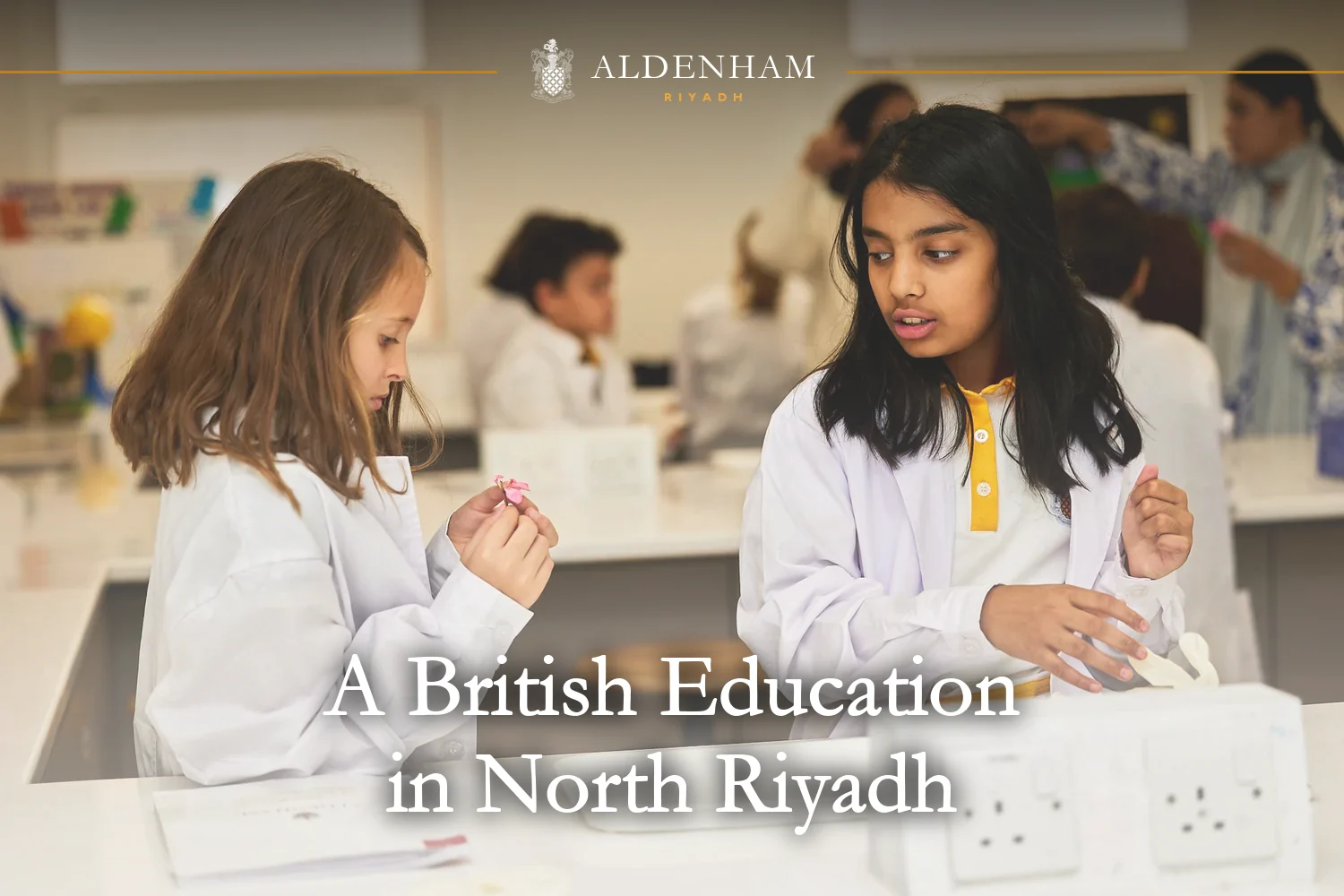 Two pupils in lab coats over their Aldenham School Riyadh uniform during a hands-on science lesson in the school lab