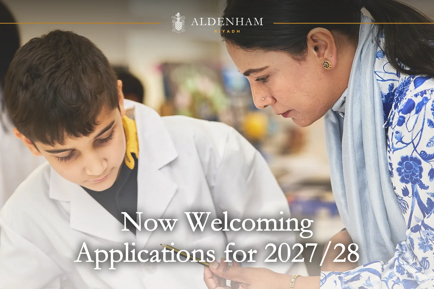 A teacher guiding a pupil in a lab coat through his notes during a science lesson at Aldenham School Riyadh