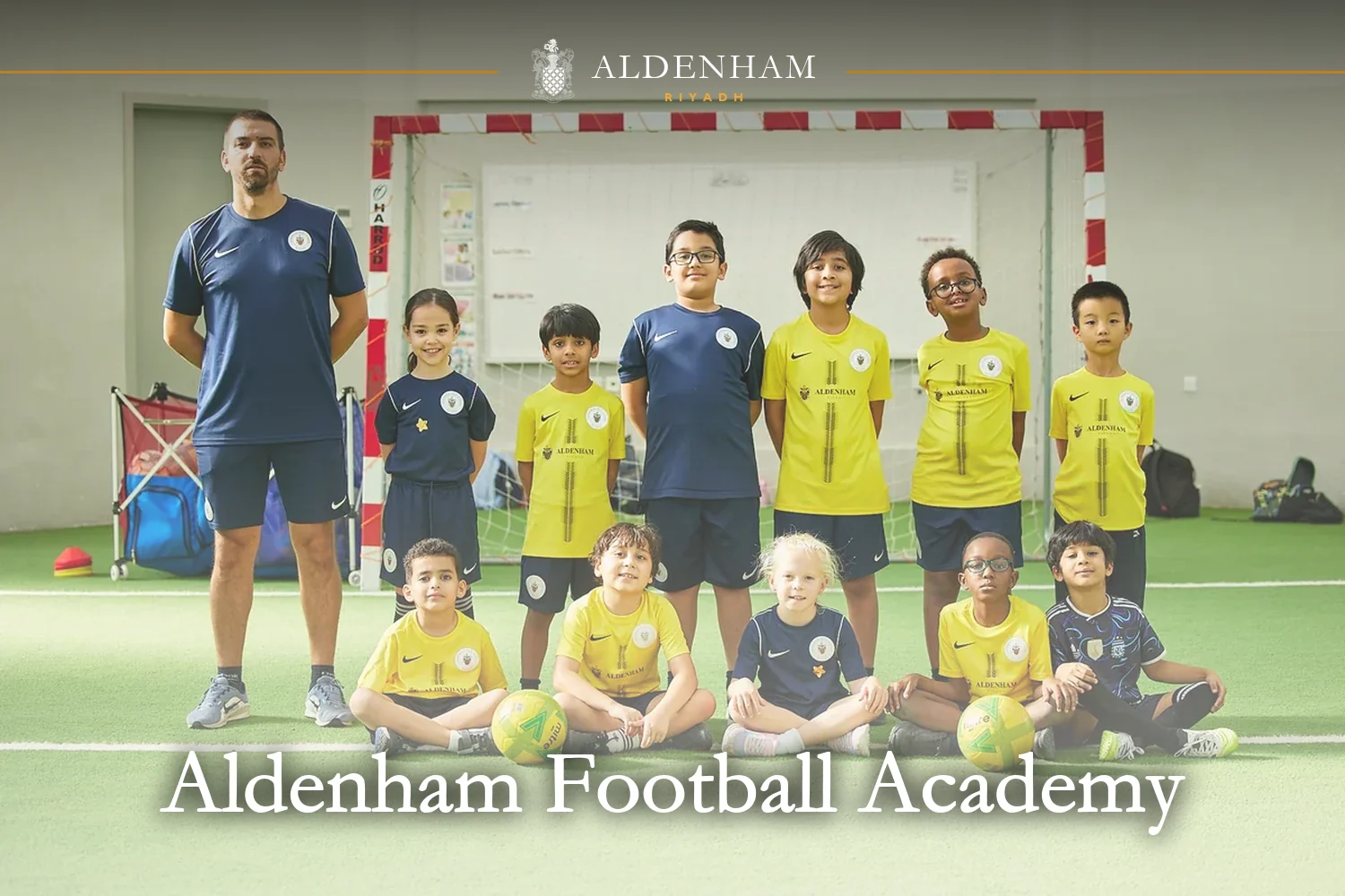 Aldenham Football Academy players in yellow and navy kit with their coach on the indoor pitch at Aldenham School Riyadh