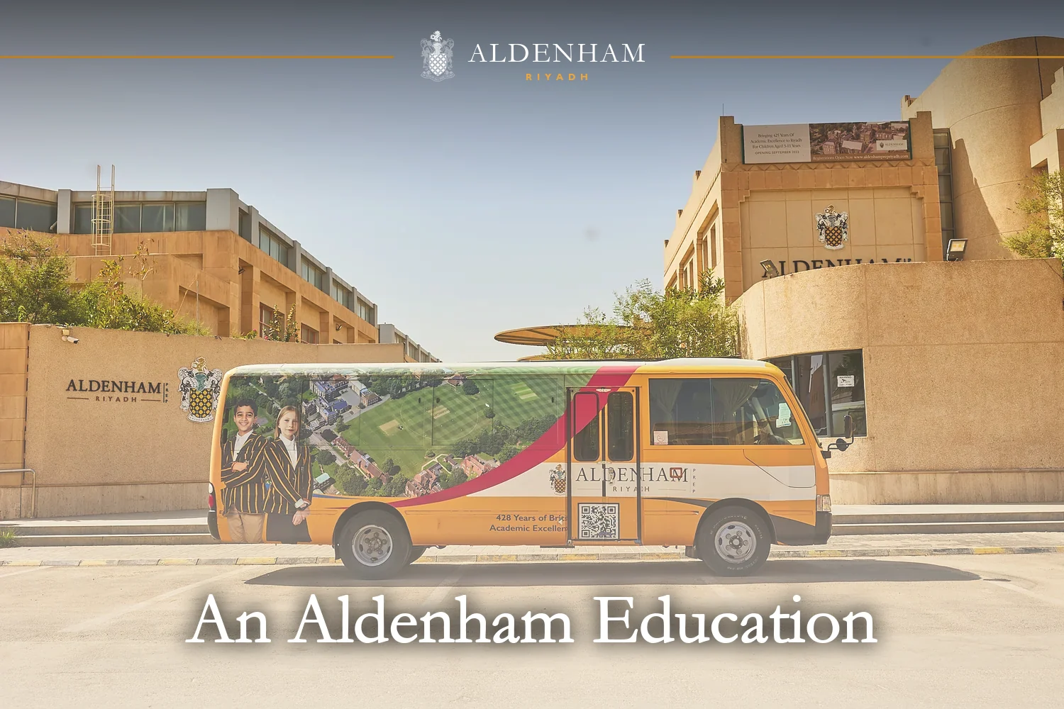 An Aldenham School Riyadh school bus parked outside the campus, with the school sign and crest behind it
